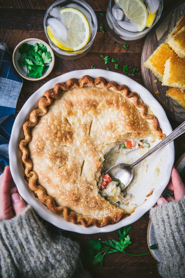 Hands holding the best chicken pot pie recipe on a wooden table.
