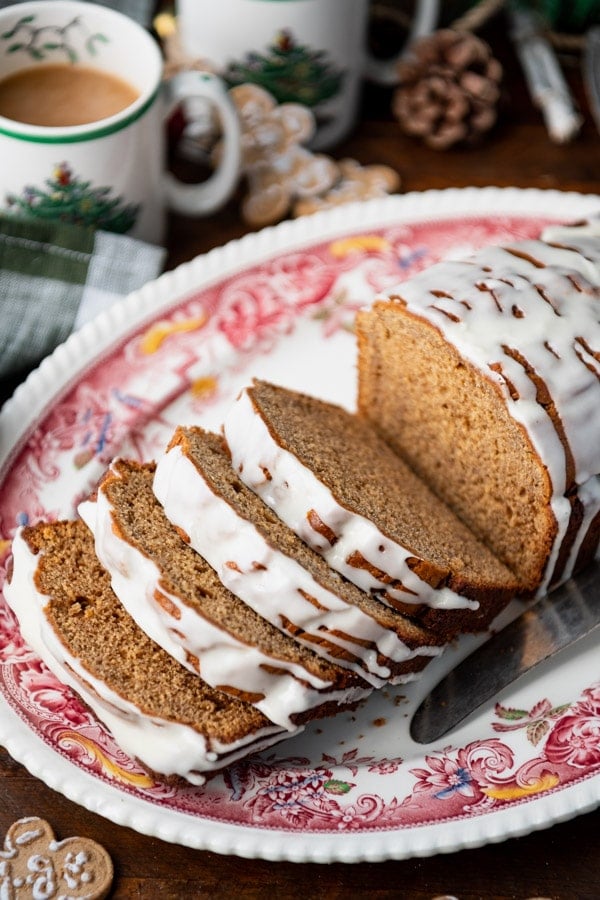 Close up side shot of a sliced gingerbread loaf with icing on a red and white platter