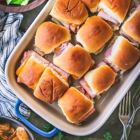 Square overhead shot of a pan of ham and cheese sliders on hawaiian rolls.