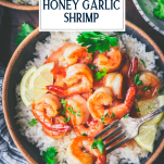 Close overhead shot of a fork in a bowl of honey garlic shrimp with text title overlay