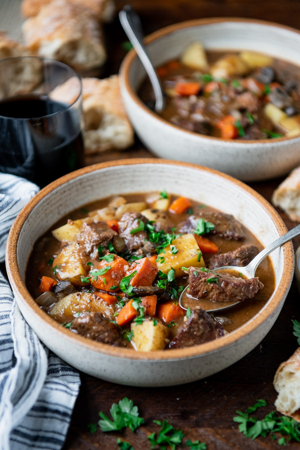 Side shot of two bowls of Irish stew on a wooden table.