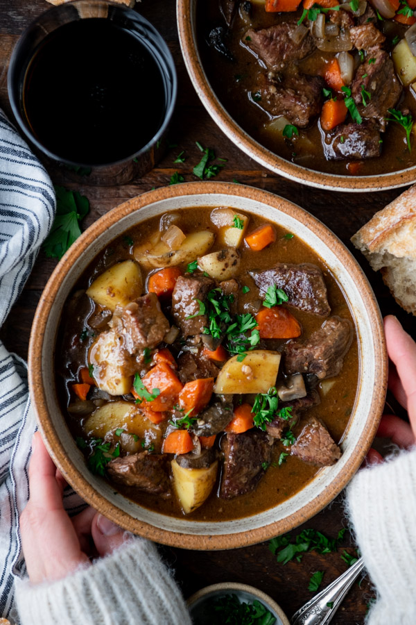 Hands holding a bowl of Guinness Irish stew