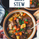 Hands eating a bowl of Guinness Irish Stew with text title overlay