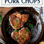 Overhead shot of two pan fried pork chops in a skillet with text title box at top