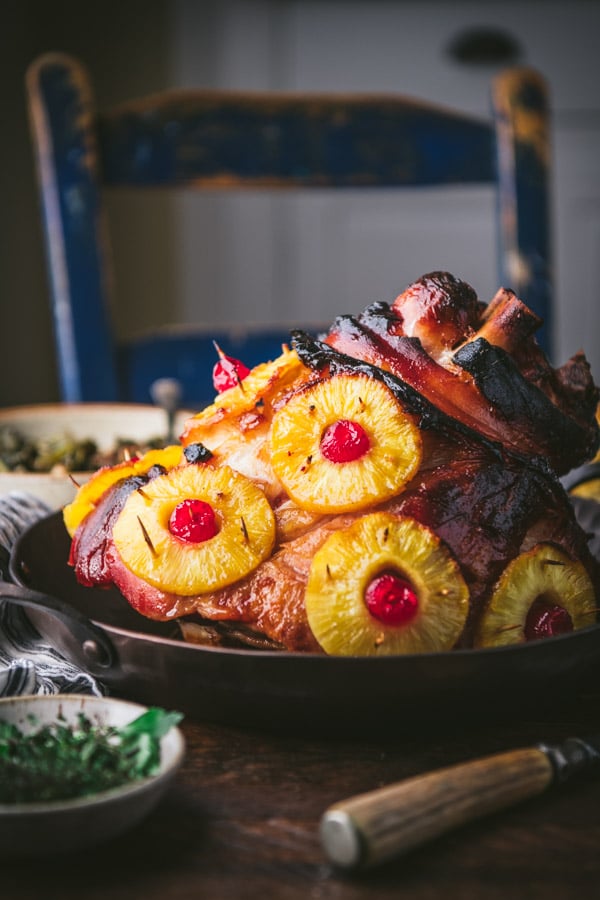 Side shot of a pineapple glazed ham on a dinner table.