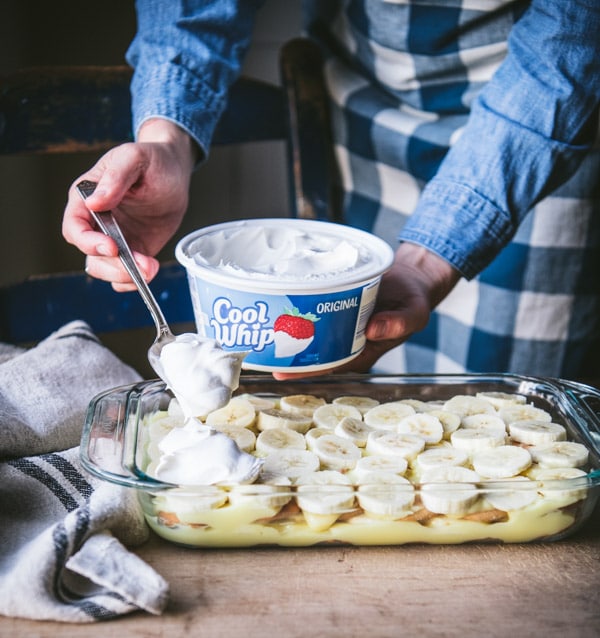Spreading cool whip on top of banana pudding.