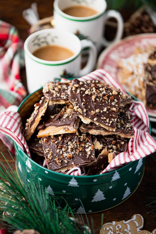 Stacks of pieces of Christmas crack toffee piled in a Christmas cookie tin.