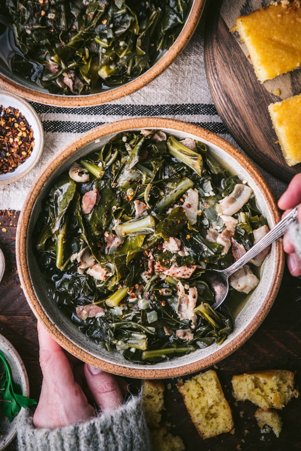 Overhead shot of hands holding a bowl of the best southern collard greens recipe.