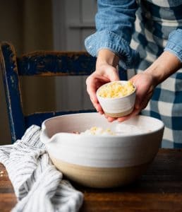 Adding cornbread crumbs to a large mixing bowl.