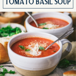 Side shot of two bowls of homemade tomato basil soup with text title box at top.