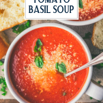 Close overhead image of a bowl of tomato soup with grated Parmesan and fresh basil on top and text title overlay