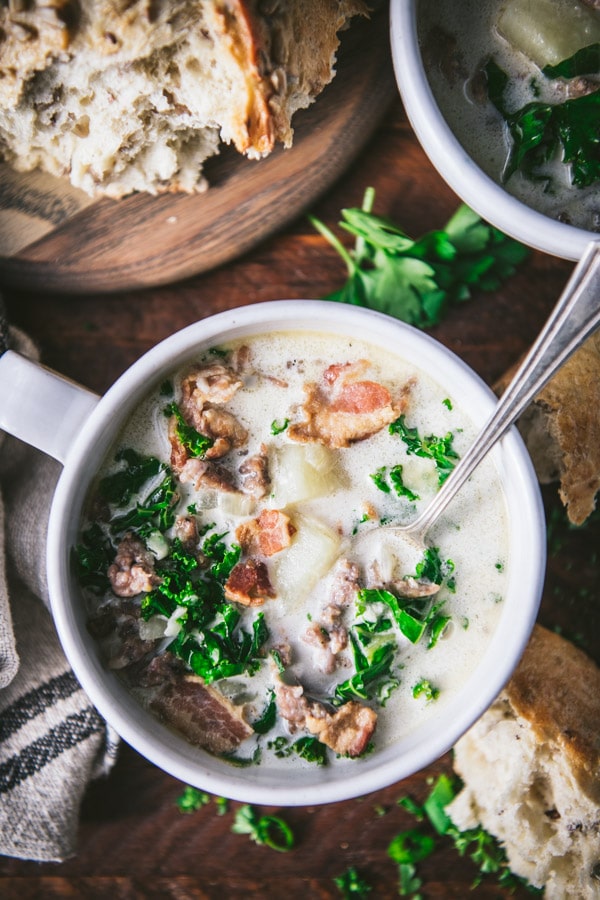 Close overhead image of a bowl of Olive Garden Zuppa Toscana with a side of bread.