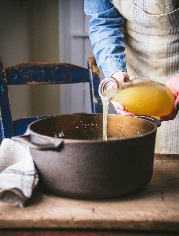 Pouring chicken broth in a pot.