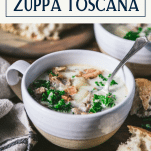 Side shot of a bowl of the best Zuppa Toscana recipe with text title box at top