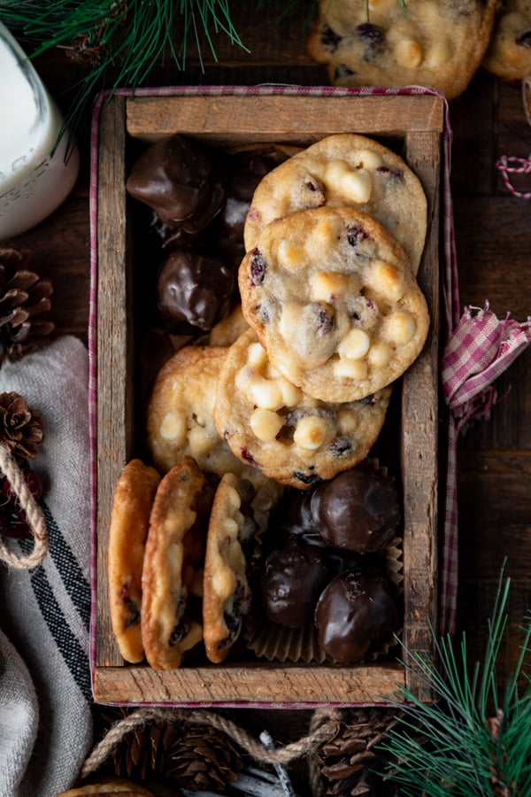 Overhead image of white chocolate chip and cranberry cookies in a wooden box with chocolate peanut butter balls
