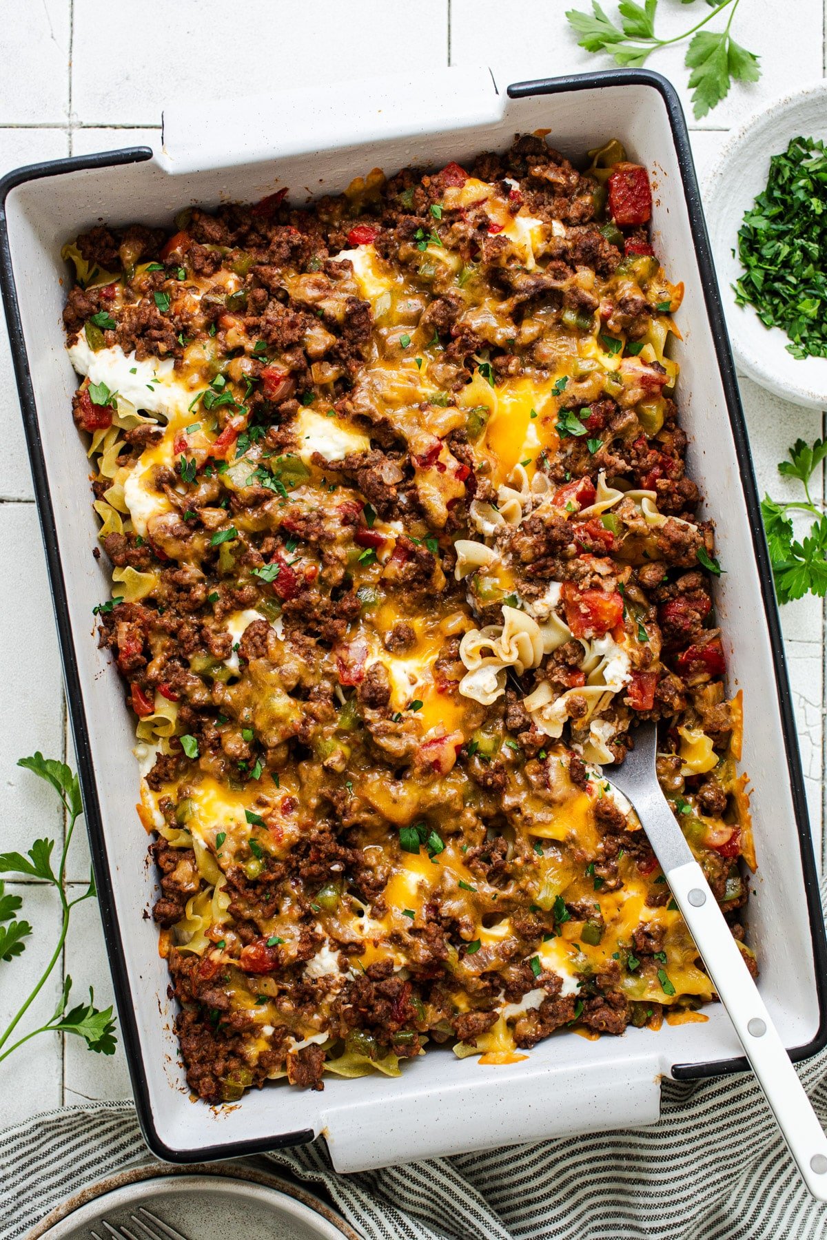 Overhead shot of an Amish hamburger casserole with noodles and sour cream in a white baking dish.