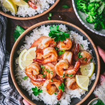 Overhead shot of hands holding a bowl of honey garlic shrimp with rice