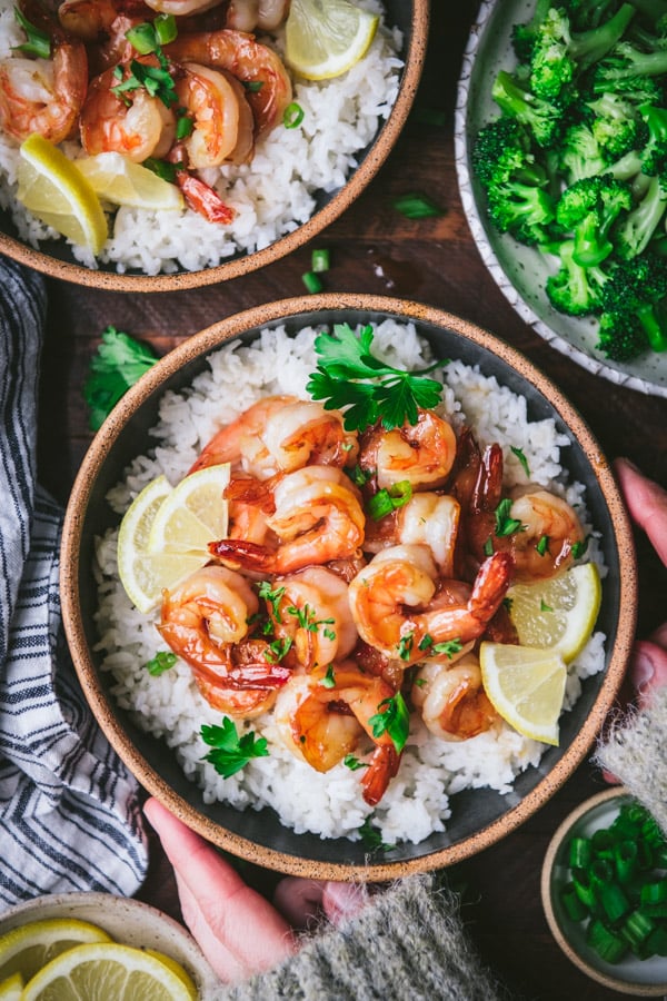 Overhead shot of hands holding a bowl of honey garlic shrimp with rice