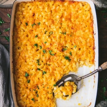 Overnight mac and cheese in a baking dish with a serving spoon.