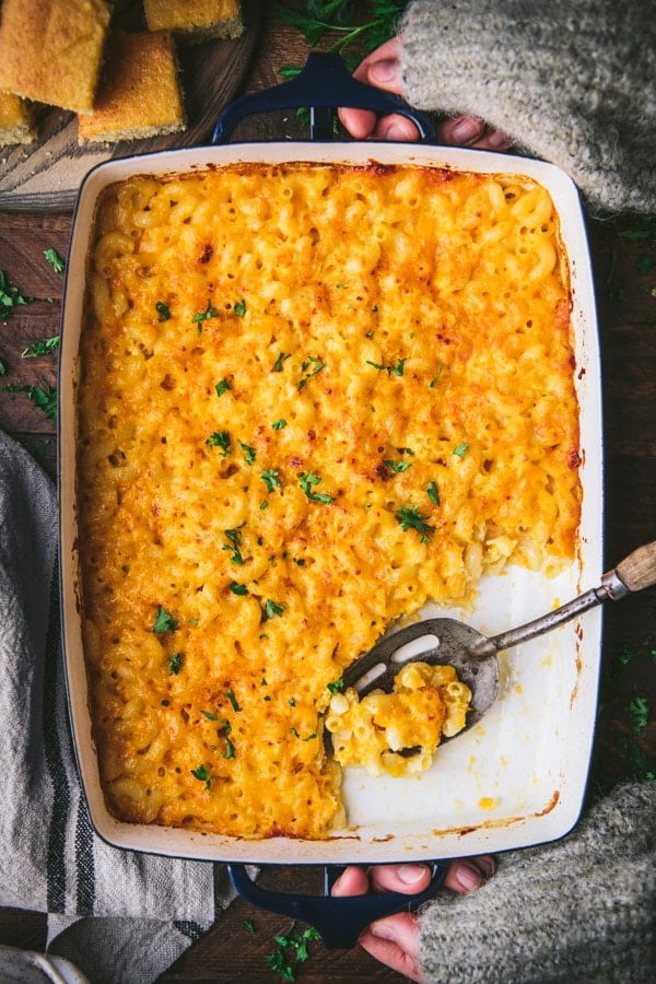 Macaroni and cheese overnight in a baking dish with a serving spoon.
