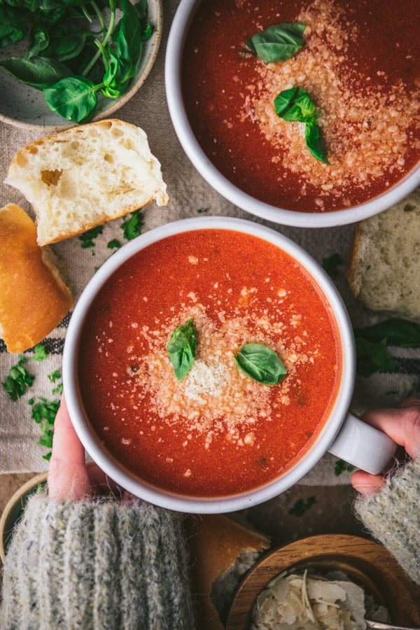 Hands holding a white mug full of the best easy tomato basil soup recipe