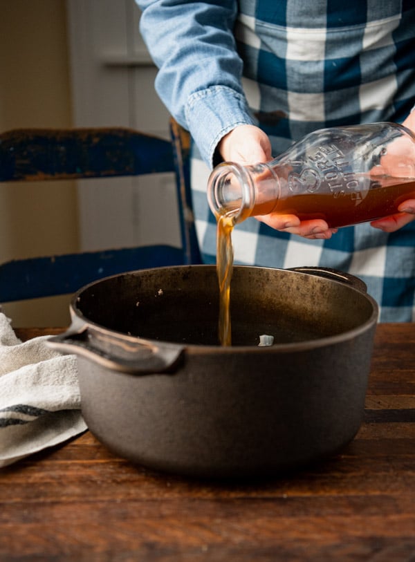 Pouring beef broth into a pot.
