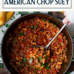 Ladle in a pot of American chop suey recipe with text title box at top.