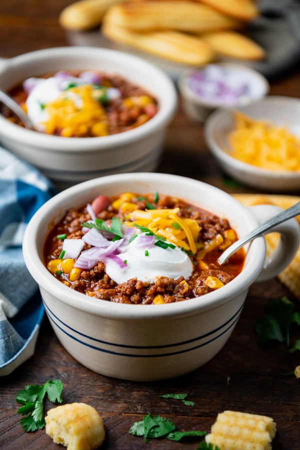 Side shot of easy beef chili recipe in a bowl with toppings.