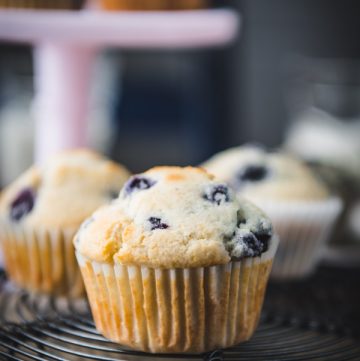 Close up side shot of a blueberry corn muffin on a cooling rack.