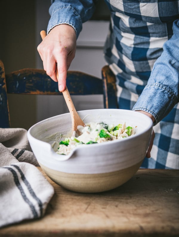 Stirring chicken and broccoli filling in a white mixing bowl.