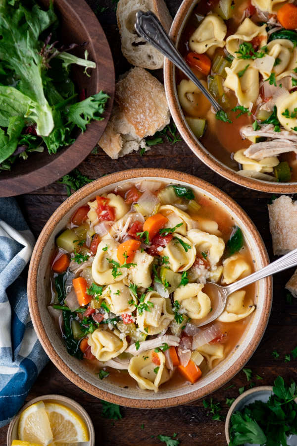 Overhead shot of a bowl of chicken tortellini soup with spinach.