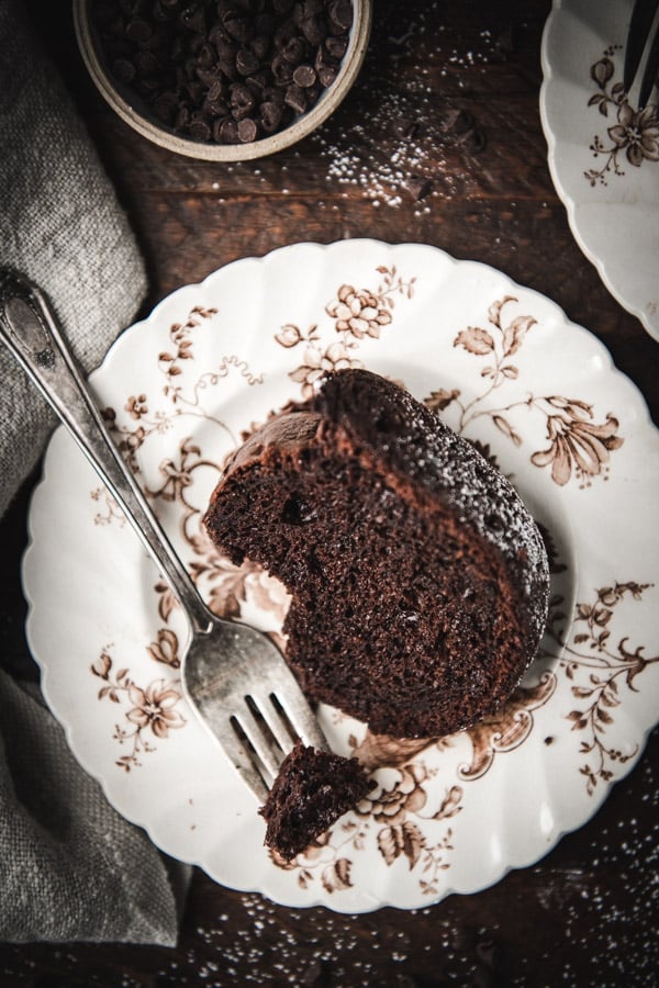 Overhead shot of a slice of chocolate bundt cake on an antique plate.