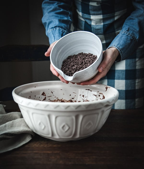 Adding chocolate chips to a white bowl.