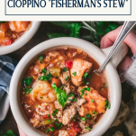 Overhead shot of hands holding a bowl of fisherman's stew cioppino with text title box at top