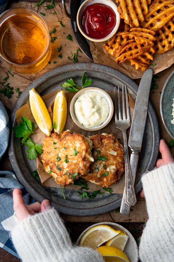 Overhead shot of hands holding a plate of Maryland crab cake recipe
