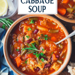 Spoon in a bowl of crock pot cabbage soup with hamburger and text title box at top.