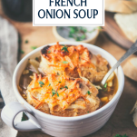 Side shot of a bowl of french onion soup on a table with text title overlay