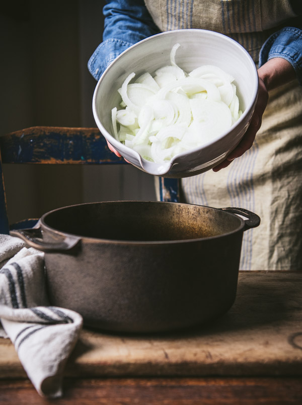 Agregar cebollas en rodajas a una olla.