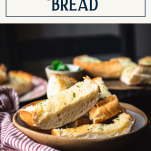Side shot of garlic bread recipe on a dinner table with text title box at top