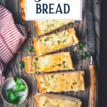 Overhead shot of a loaf of sliced garlic bread recipe with text title overlay