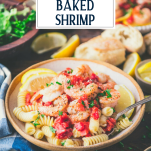 Side shot of a bowl of easy Italian baked shrimp served over pasta with text title overlay