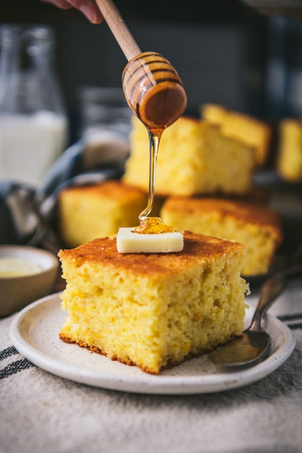 Drizzling honey on a slice of thick cornbread.
