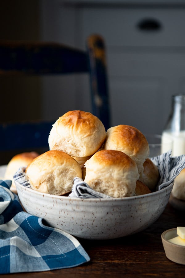 Side shot of a bowl of no knead dinner rolls on a table