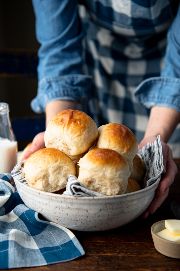 Side shot of hands holding a basket of the best dinner roll recipe