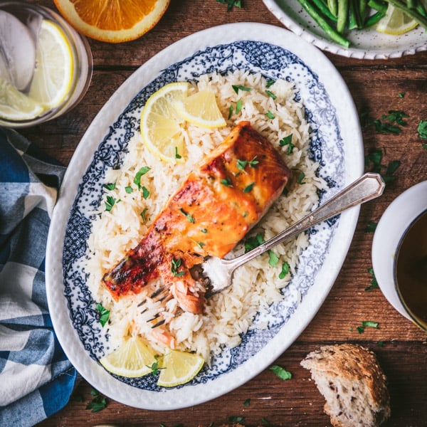 Square overhead shot of a plate of orange salmon with rice and green beans.