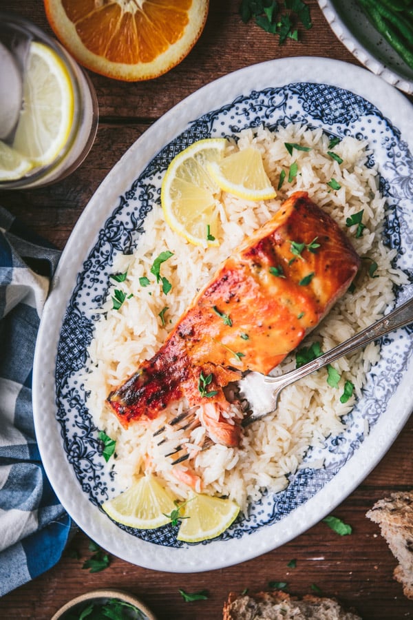 Close overhead shot of a slice of orange glazed salmon with rice and lemon wedges.