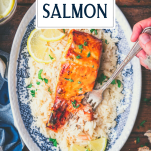 Hands using a fork to eat orange glazed salmon with text title overlay