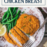 Close up overhead shot of oven fried chicken breast on a plate with green beans and text title box at top