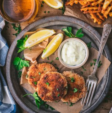 Overhead shot of three salmon patties on a plate with a side of fries and coleslaw