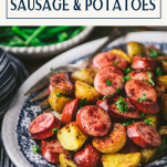 Close up side shot of a tray of sheet pan sausage and potatoes with text title box at top